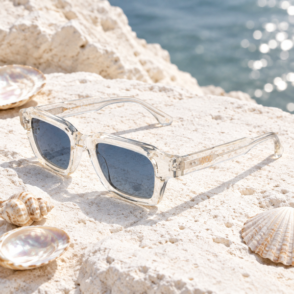 Lunettes de soleil Litchi posées sur une pierre blanche avec des coquillages nacrés